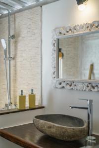a bathroom with a stone sink and a mirror at Ora Villas Gili Meno in Gili Meno