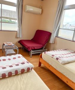 um quarto com duas camas e uma cadeira e uma janela em フェーヌカジ洋室 em Ilhas Miyako