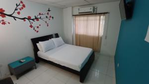 a bedroom with a bed and a tree mural on the wall at Hostal Casa del Sol in Santa Marta