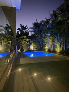 un patio trasero con piscina por la noche con luces en Byron Bay Holiday Homes - Marie and Fred's Villa, en Byron Bay