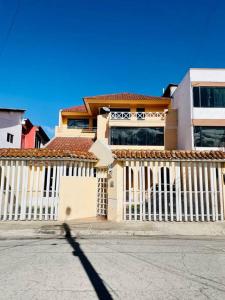 una casa con una cerca blanca delante de ella en Mi Casa en Rio, en Riobamba