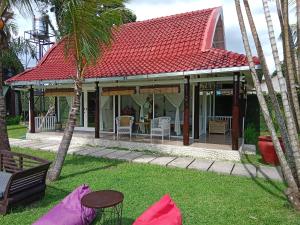 uma casa com um telhado vermelho e algumas palmeiras em Le Kekeri Villas Collection em Mataram