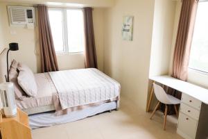 a bedroom with a bed and a desk and a window at Spacious 1BR Corner Unit in IT Park in Cebu City