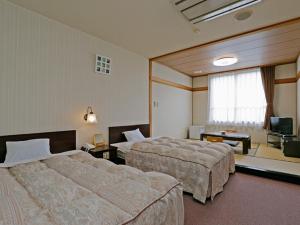 a hotel room with two beds and a television at Ashinomaki Prince Hotel in Aizuwakamatsu