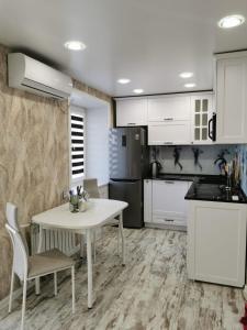 a kitchen with a white table and a refrigerator at Тихая гавань in Ustʼ-Kamenogorsk