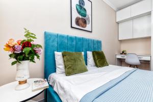 1 dormitorio con 1 cama con cabecero azul y un jarrón de flores en Новая квартира в самом центре города, en Astana