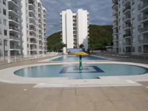 ヒラルドットにあるEspléndido y Fantástico Apartamento en Girardot. 4 Piscinas, WiFi, Parque infantil, Parqueadero privado.の黄色い傘を中心に置いたスイミングプール