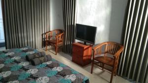 a bedroom with a bed and two chairs and a tv at Risal Guest House in Munggu