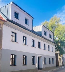 a white building with black windows on a street at Bezbariérové apartmány se zahrádkou in Chrastava