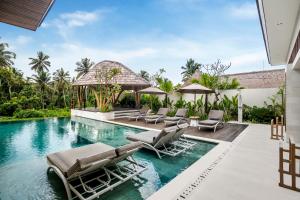 a swimming pool with chaise lounges and chairs at Villa Pearl by BaliSuperHost in Ubud