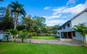 a house with a lawn and palm trees at Nyumbani Palace Arusha in Arusha