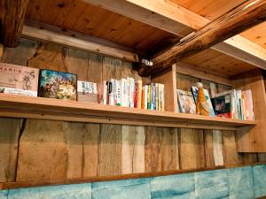półka wypełniona książkami na drewnianej ścianie w obiekcie GOYADO w mieście Ozu