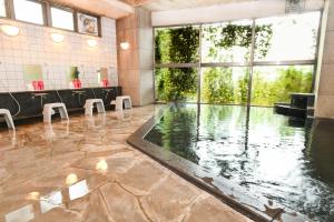 a swimming pool in a room with a large window at ＹＵＦＵＩＮ　ＦＬＯＲＡＬ　ＶＩＬＬＡＧＥ　ＨＯＴＥＬ in Yufuin
