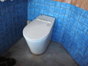 a bathroom with a toilet in a blue tiled wall at HealingDragon Ryugu cottage in Shimoda