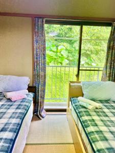 宮崎市にあるShirahama Harborのベッドルーム1室(ベッド2台付)、窓、バルコニーが備わります。