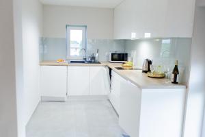 a white kitchen with a sink and a microwave at Hotel Pogoria Residence in Dąbrowa Górnicza