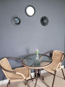 une table en verre avec des chaises et un vase avec des fleurs. dans l'établissement PyoLi Guesthouse, à Seogwipo