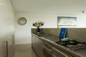 uma cozinha com fogão e um relógio na parede em Modern & Sleek, Minutes to the City. Parking/Pool em Sydney