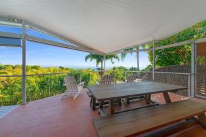 a patio with a wooden table and chairs on a deck at Lee Lane Beach House - Lighthouse Rd Byron in Byron Bay