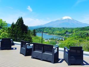 three chairs on a deck with a mountain in the background at Rokumeikan Hills in Yamanakako
