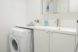 uma lavandaria branca com um lavatório e uma máquina de lavar roupa em Snowflake Suites II em Rovaniemi