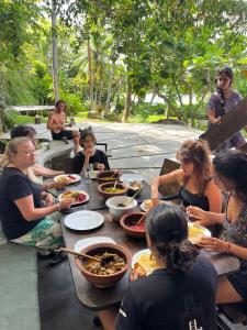 un grupo de personas sentadas alrededor de una mesa comiendo comida en TheLakeHostel en Hikkaduwa