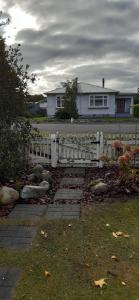 a white fence in front of a house at Bunny Cottage in Masterton