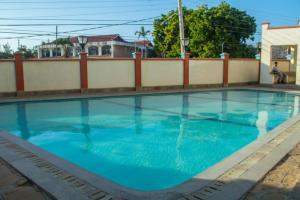 una piscina con acqua blu di fronte a una recinzione di Lux Suites Royal Family Apartment Nyali a Mombasa