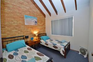 Cette chambre comprend 2 lits et un mur en briques. dans l'établissement Tropical Hideaway - Kalbarri WA, à Kalbarri