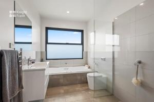 y baño con bañera, aseo y lavamanos. en As new beachside luxury villa with stunning views, en Kingston Beach