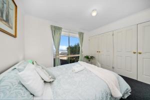 a white bedroom with a large bed with a window at Hobart Vista in Hobart