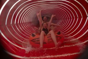 Zwei Mädchen fahren einen Jet Ski durch einen Tunnel. in der Unterkunft Ferien- und Freizeitpark Weissenhäuser Strand in Weissenhäuser Strand