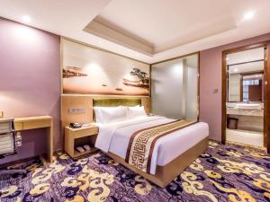 Cette chambre comprend un grand lit et une télévision. dans l'établissement Guangzhou Huihe Hotel, à Canton