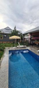 ein großer Pool mit Sonnenschirm und Stühlen in der Unterkunft Elnr Small swing pool villa in Daşca