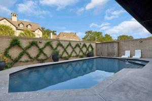 a swimming pool in a backyard with two white chairs at Lovely 4BD House w pool, hot tub and free parking in Houston