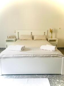a white bed in a room with two tables at PLANTZOUNAKIS in Áno Viánnos