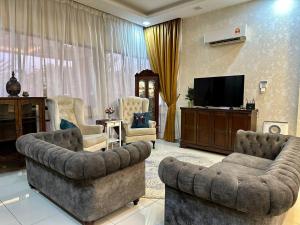 a living room with two couches and a flat screen tv at Retreat Saujana rawang in Rawang
