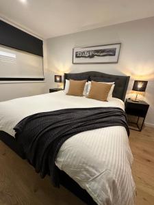 - une chambre avec un grand lit blanc et des oreillers bruns dans l'établissement Palko - Luxury In the City, à Canberra