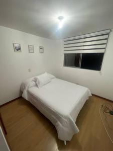 een wit bed in een kamer met een raam bij Apartamento en el poblado con vista ala ciudad in Medellín