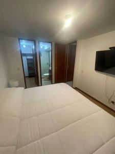 een slaapkamer met een groot wit bed en een flatscreen-tv bij Apartamento en el poblado con vista ala ciudad in Medellín
