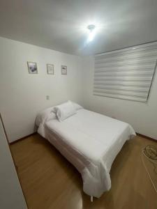 een wit bed in een kamer met een raam bij Apartamento en el poblado con vista ala ciudad in Medellín