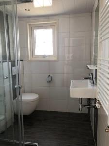 La salle de bains est pourvue d'un lavabo, de toilettes et d'une fenêtre. dans l'établissement Vakantiehuis voor 6 personen, à Opheusden