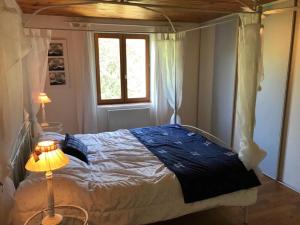 a bedroom with a bed and a lamp and a window at La Roderie in Abjat