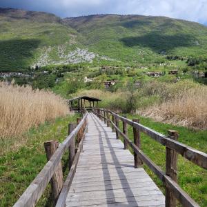 La casa di Ale في إندين جياناو: ممشى خشبي فوق حقل مع جبال في الخلفية +12 صورة
