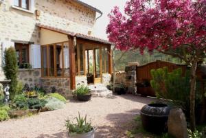 um jardim com uma casa e uma árvore com flores cor-de-rosa em La Roderie em Abjat