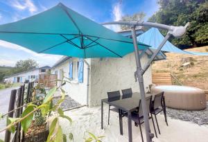 a blue umbrella sitting next to a table with chairs at Gîte 4/6 personnes La mélodie du bonheur in Habas