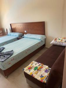 um quarto com 2 camas e um sofá em قريه اكوا فيو الساحل الشمالي em El Alamein