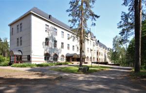 ein weißes Gebäude mit einem Baum davor in der Unterkunft Forenom Hostel Röykkä in Helsinki