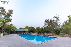 une grande piscine avec des chaises et un bâtiment dans l'établissement Vanaashrya Resort and Spa Sariska, à Tehla