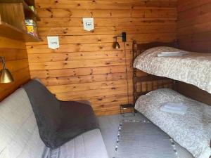 two beds in a room with wooden walls at Chalet cosy, cadre apaisant in Saint-Léonard